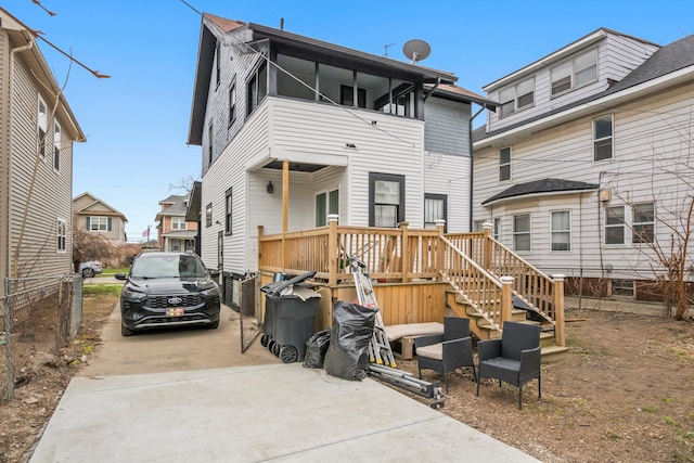 back of house featuring concrete driveway and fence