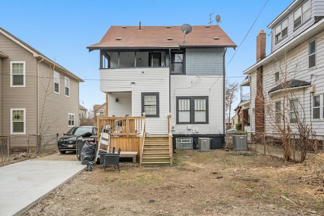 back of property featuring concrete driveway and central AC unit