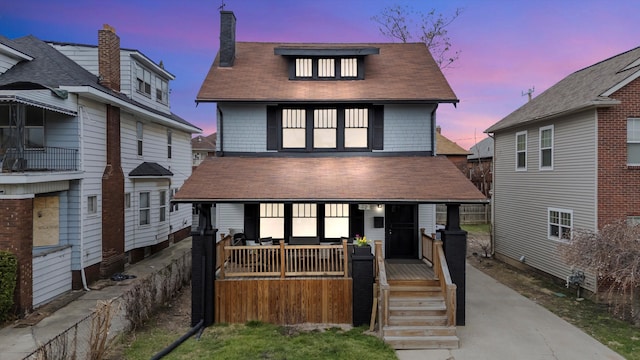 american foursquare style home featuring roof with shingles, a chimney, and covered porch