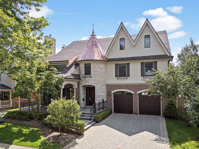 french country home with a shingled roof, stone siding, a garage, fence, and driveway
