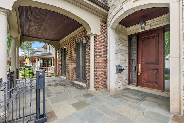 view of exterior entry with brick siding and a porch