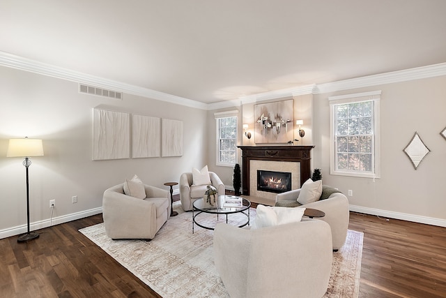 living room featuring a glass covered fireplace, baseboards, crown molding, visible vents, and wood finished floors