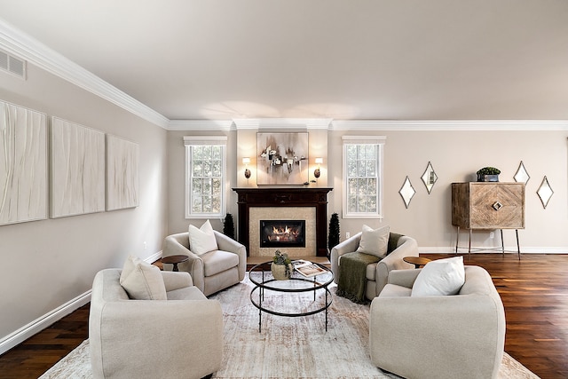 living room featuring visible vents, baseboards, ornamental molding, wood finished floors, and a glass covered fireplace
