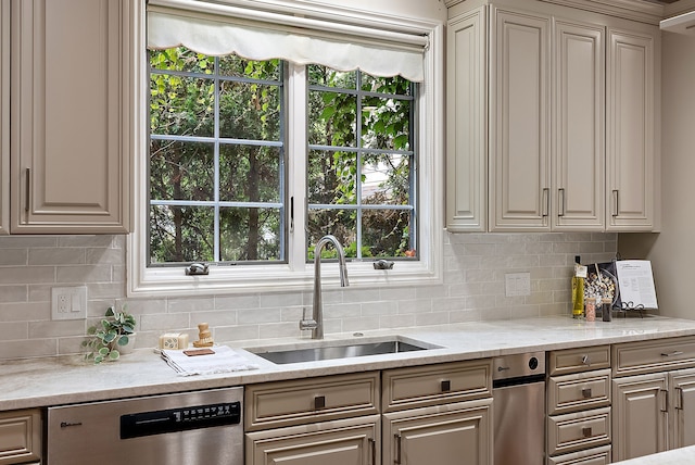 kitchen with a sink, backsplash, dishwasher, and light stone countertops