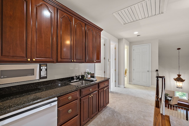 kitchen with a sink, white appliances, recessed lighting, dark stone counters, and light carpet