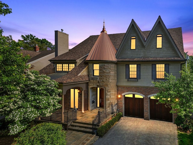 view of front of house featuring stone siding, a garage, fence, decorative driveway, and roof with shingles