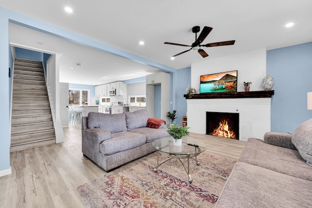 2533 Virginia Park St, Detroit, MI 48206 - living room featuring ceiling fan, light wood-style floors, a brick fireplace, and stairs