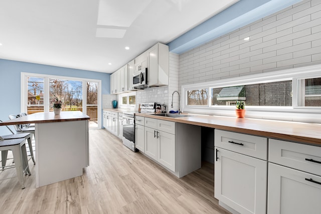 2533 Virginia Park St, Detroit, MI 48206 - kitchen featuring tasteful backsplash, a kitchen breakfast bar, wood counters, appliances with stainless steel finishes, and a sink