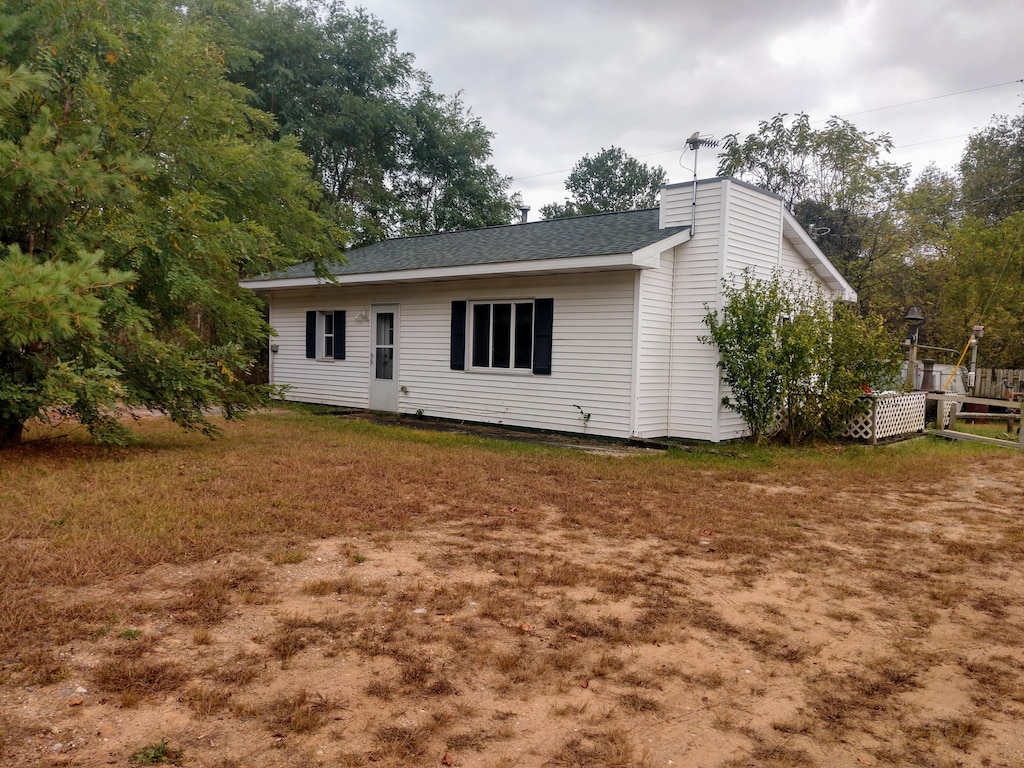 rear view of property featuring a chimney and a shingled roof