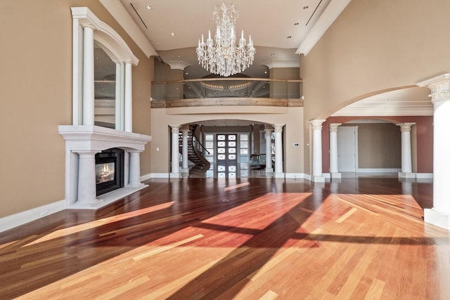 82 Chateaux Du Lac, Fenton, MI 48430 - entrance foyer featuring ornate columns, a glass covered fireplace, a high ceiling, and wood finished floors