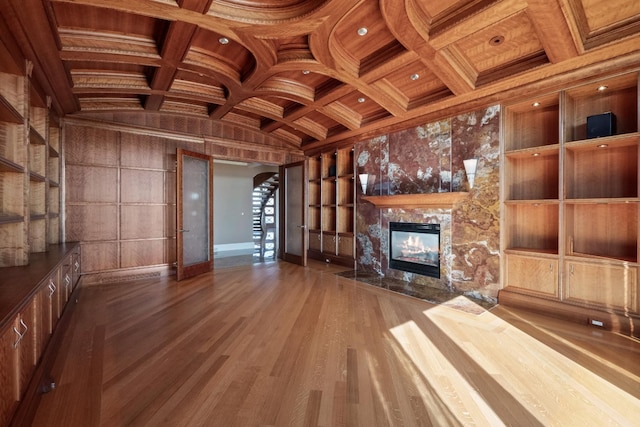 82 Chateaux Du Lac, Fenton, MI 48430 - unfurnished living room featuring arched walkways, built in shelves, wood finished floors, a high end fireplace, and beamed ceiling