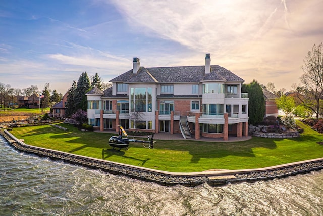 82 Chateaux Du Lac, Fenton, MI 48430 - rear view of house featuring a chimney, a lawn, a patio, a balcony, and a water view