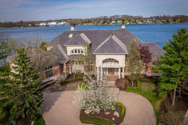 82 Chateaux Du Lac, Fenton, MI 48430 - french country inspired facade with a water view, curved driveway, a chimney, and stone siding