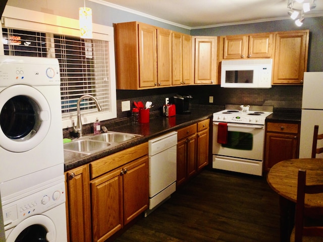 kitchen with dark countertops, stacked washing maching and dryer, white appliances, and a sink