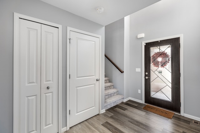 foyer entrance with stairs, baseboards, and wood finished floors