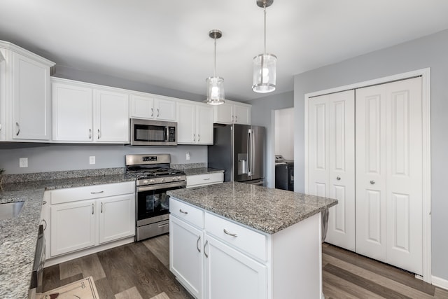 kitchen featuring a center island, white cabinets, light stone countertops, dark wood finished floors, and stainless steel appliances