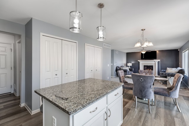 kitchen featuring an inviting chandelier, light stone countertops, white cabinetry, visible vents, and dark wood-style flooring