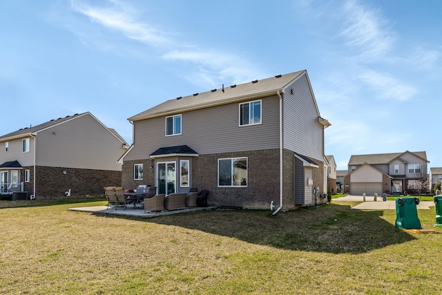 rear view of property with a lawn, a patio area, and brick siding