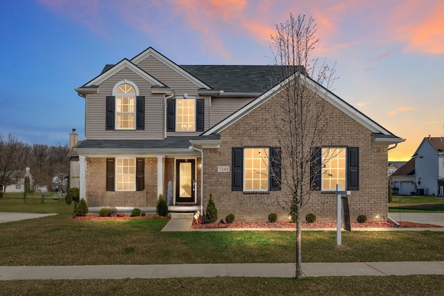 traditional-style house featuring a front yard and brick siding