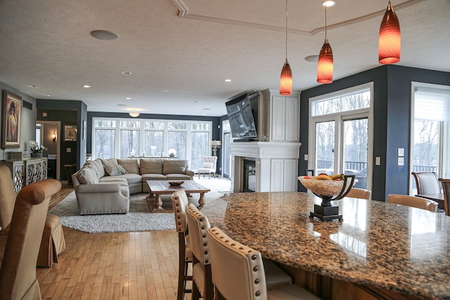 dining room featuring light wood-style flooring, plenty of natural light, a glass covered fireplace, and a textured ceiling