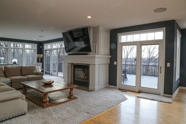 living room featuring recessed lighting, light wood-style flooring, baseboards, and a large fireplace