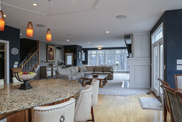 living room featuring light wood-style flooring, recessed lighting, plenty of natural light, and stairway
