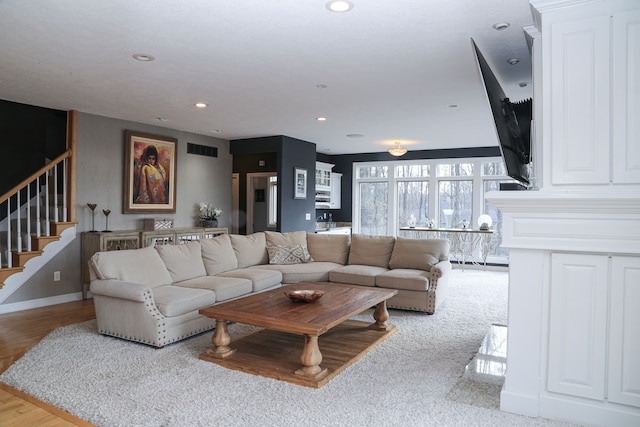 living room featuring a baseboard heating unit, baseboards, recessed lighting, stairway, and visible vents