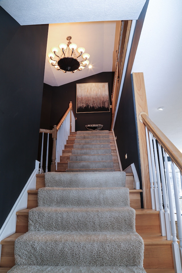 stairway with a notable chandelier and lofted ceiling