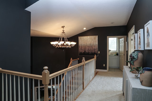 hall featuring baseboards, an inviting chandelier, an upstairs landing, light colored carpet, and lofted ceiling