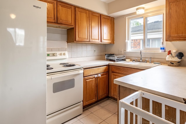 kitchen with white appliances, a sink, light countertops, brown cabinets, and decorative backsplash