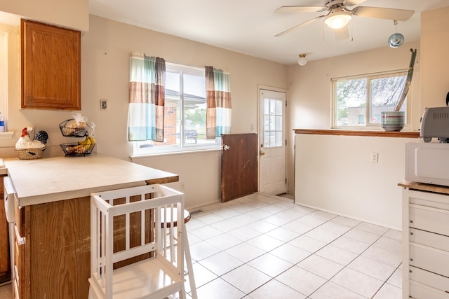dining space with ceiling fan, baseboards, and light tile patterned floors