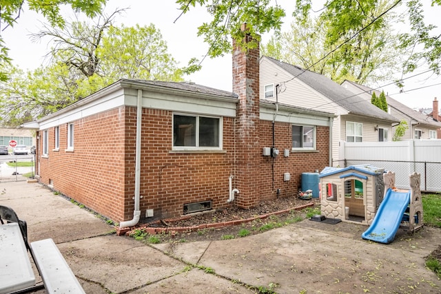 back of property with brick siding, fence, a chimney, and a patio area