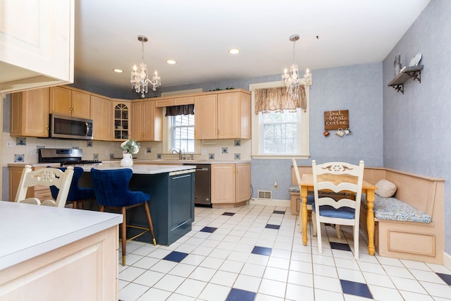 kitchen featuring a chandelier, stainless steel appliances, light countertops, a sink, and a breakfast bar area