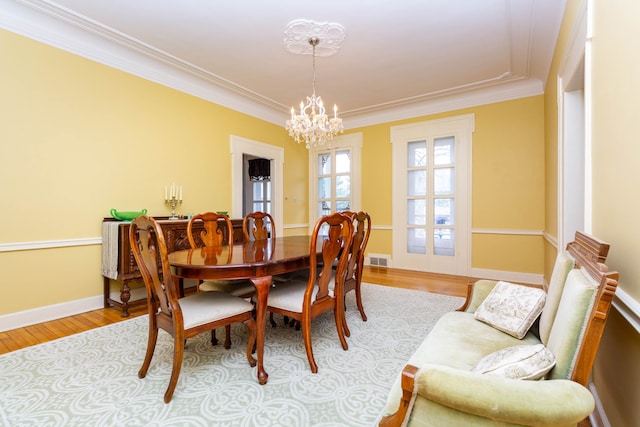 dining space featuring a chandelier, crown molding, light wood-style floors, and baseboards