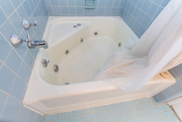 bathroom with a tub with jets and tile patterned floors