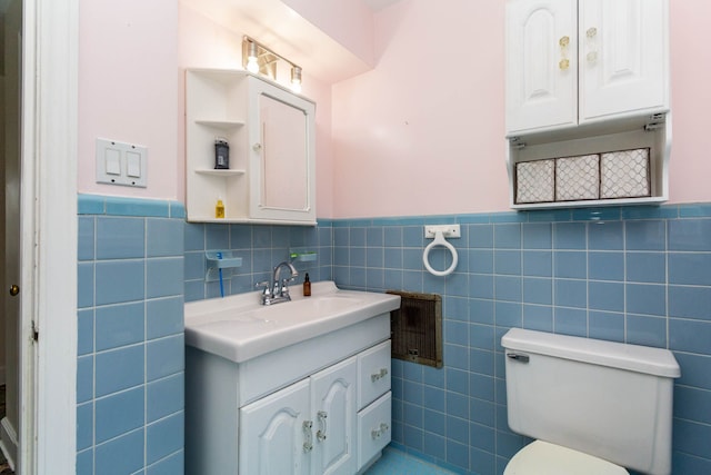 bathroom featuring tile walls, a wainscoted wall, vanity, and toilet