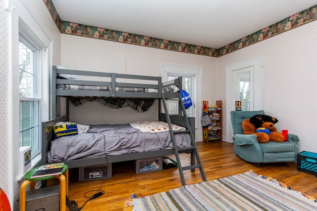 bedroom with wallpapered walls and wood finished floors