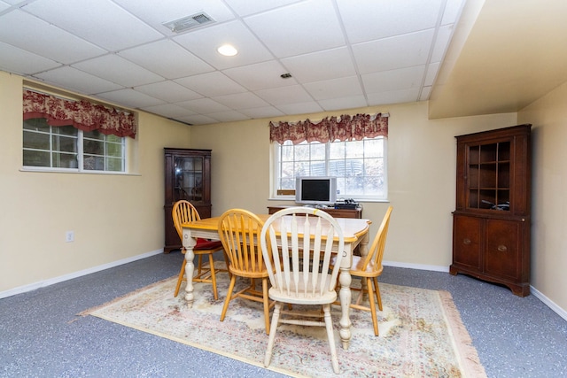 dining area featuring baseboards and a drop ceiling