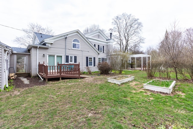 back of property featuring a vegetable garden, a wooden deck, and a lawn