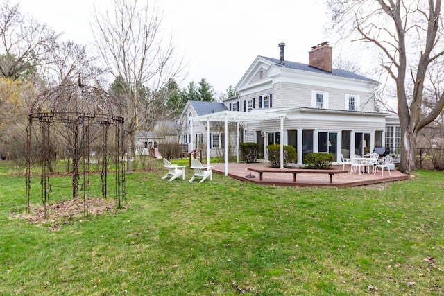 rear view of house featuring a deck, a chimney, and a yard