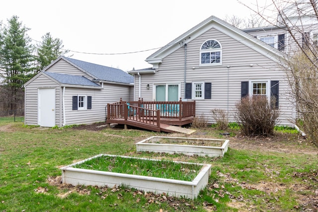 rear view of property featuring a wooden deck, a lawn, and a garden