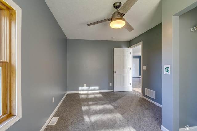 spare room with carpet, visible vents, baseboards, and a ceiling fan