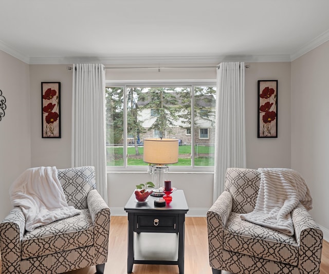 sitting room with plenty of natural light, ornamental molding, and light wood-style floors