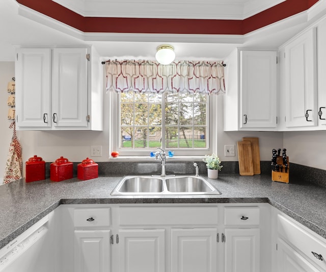 kitchen with white cabinets, dark countertops, a sink, and dishwasher