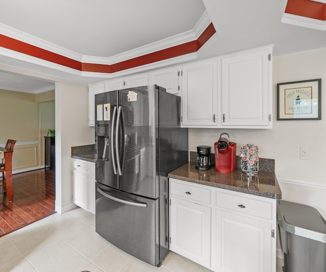 kitchen featuring dark stone counters, white cabinetry, stainless steel fridge, and ornamental molding