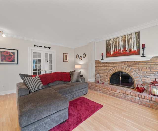living area featuring ornamental molding, wood finished floors, a fireplace, baseboards, and french doors