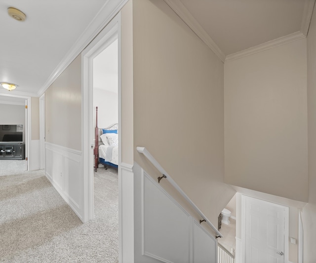 hall featuring crown molding, a wainscoted wall, carpet flooring, and an upstairs landing
