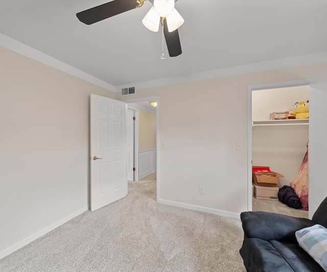sitting room featuring carpet floors, ceiling fan, visible vents, and crown molding