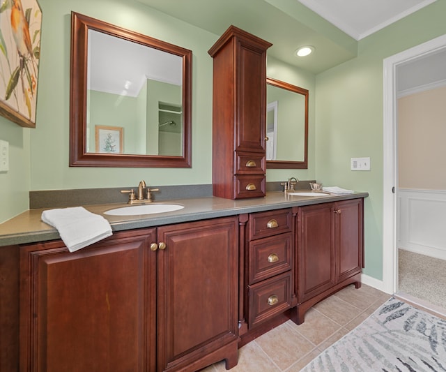 bathroom with crown molding, double vanity, tile patterned floors, and a sink