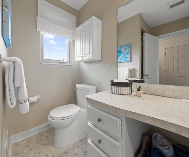 bathroom with baseboards, vanity, toilet, and visible vents